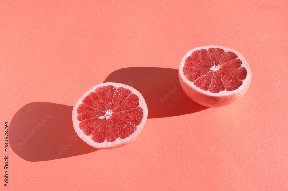 Ripe pink sliced grapefruit on soft pink background. Citrus fruit