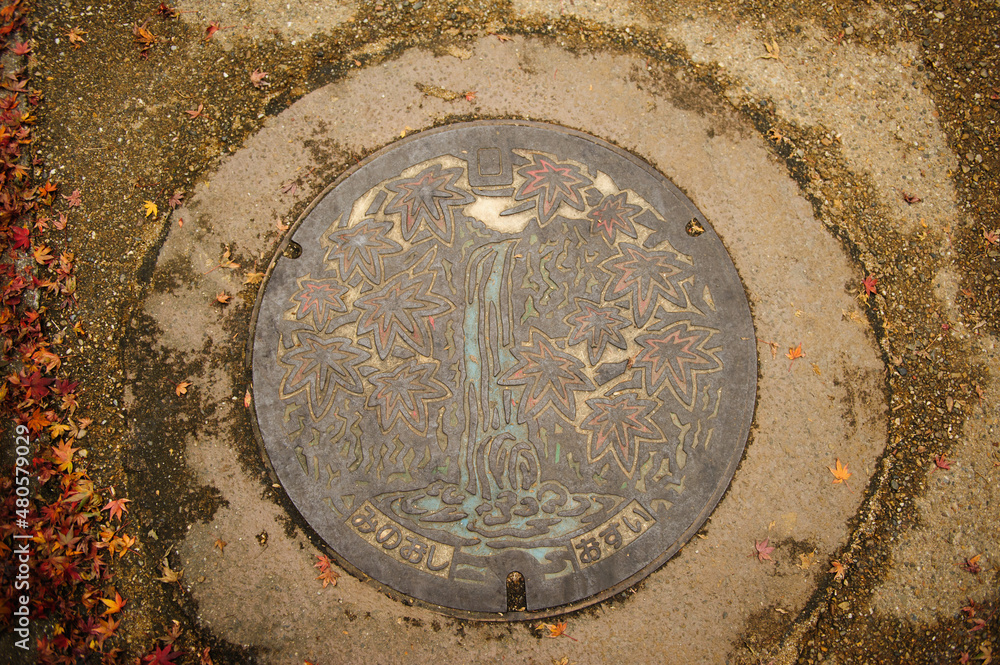 Minoo Falls and maple leaves painted on a manhole cover in Minoo City