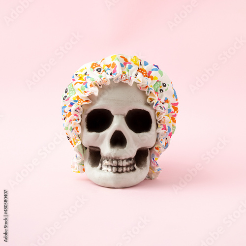 Colorful bathing cap on the skull. A humorous minimalist concept on a pink background
