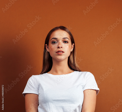 young pretty girl with blond hair posing cheerful on brown background, lifestyle people concept