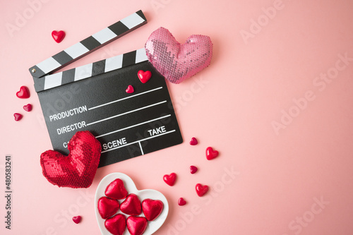 Obraz na plátně Happy Valentines day and romantic movie concept with  movie clapper board, heart shapes and chocolates on pink background