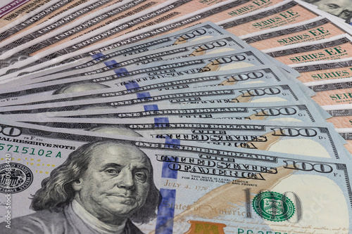 US Savings Bonds and 100 Dollar bills, representing investment choices. Savings bonds are debt securities issued by the U.S. Department of the Treasury and issued in Series EE or Series I.