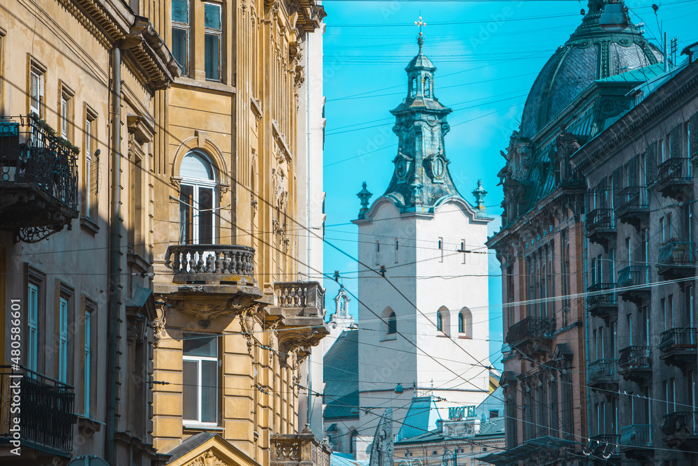 view of lviv street with cathedral church tower between buildings