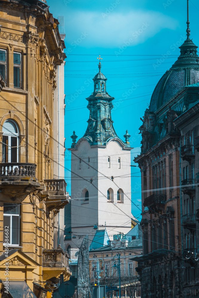 view of lviv street with cathedral church tower between buildings