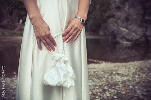 Close-up of bride holding white wedding bag. Copy space