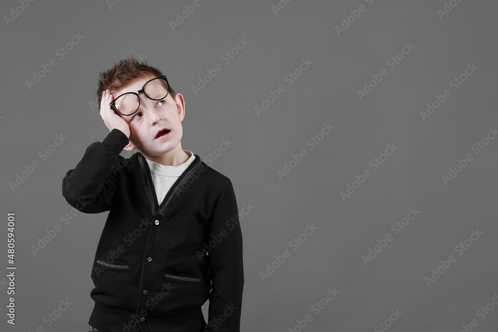 Sad unhappy schoolboy in eyewear having painful look, holding hand on his forehead. Frustrated sick child suffering form terrible headache Sad unhappy schoolboy in eyewear having painful look, holding hand on his forehead. Frustrated sick child suffering form terrible headache