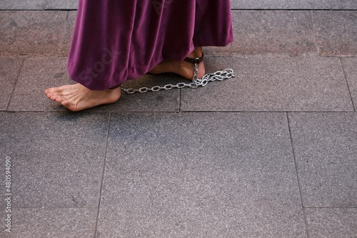 Feet of a barefoot man walking in chains through the streets of the city in a typical Andalusian procession. Religious robe is carried by a man without shoes. Pain in the feet when walking barefoot photo