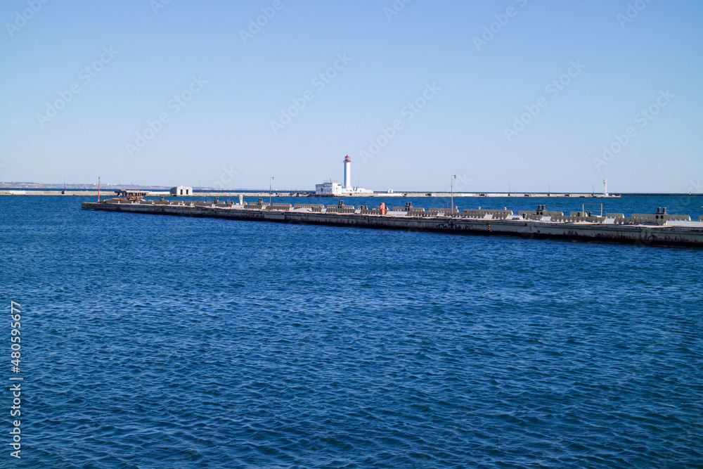 a seaport on the seashore, a lighthouse is visible in the distance, a beautiful blue sea