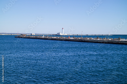 a seaport on the seashore, a lighthouse is visible in the distance, a beautiful blue sea