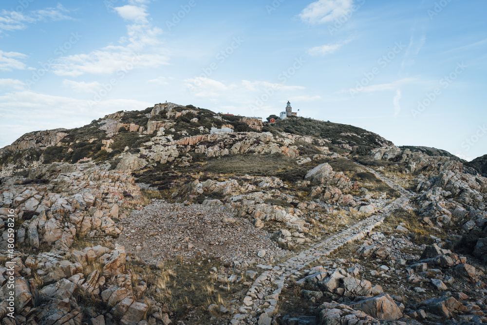 Naklejka premium Kullaberg lighthouse on the rocky coast at Kullaberg nature reserve in south Sweden. Popular tourist destination for hiking.