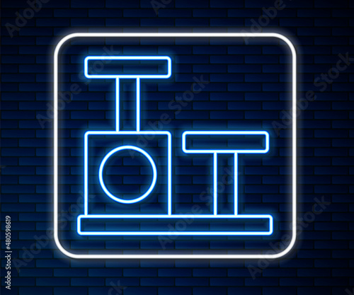 Glowing neon line Cat scratching post with toy icon isolated on brick wall background. Vector