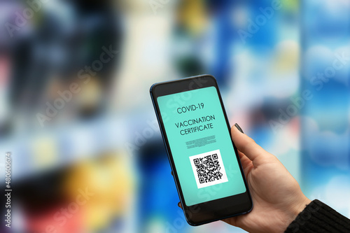 vaccination passport for a grocery store,hand with a phone with a qr code certificate for proof of coronavirus vaccination to get to the supermarket