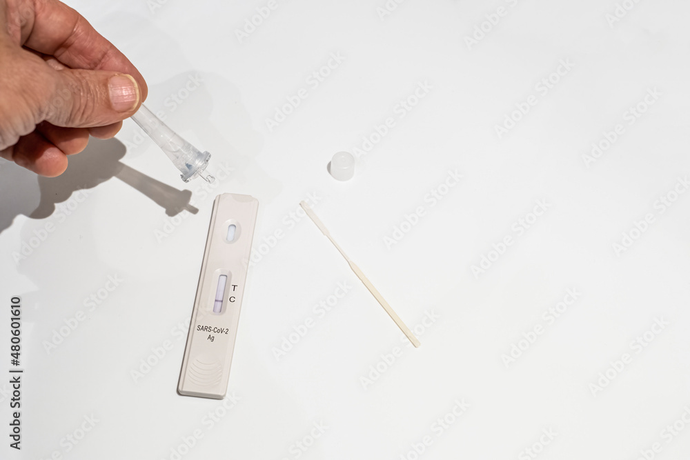 a hand with an eyedropper droplet on an antigen test for corona virus detection, omicron variant, white background, selective focus on the receptor, negative result, copy space a hand with an eyedropper droplet on an antigen test for corona virus detection, omicron variant, white background, selective focus on the receptor, negative result, copy space