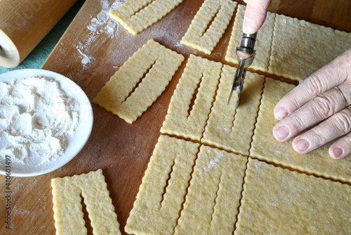 Mani donna che preparano i tradizionali dolci di carnevale italiani chiamati chiacchiere su sfondo bianco. Copia spazio. Direttamente sopra. photo