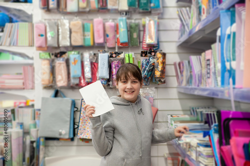 Portrait of teenage girl in gray hoodie in stationery store.