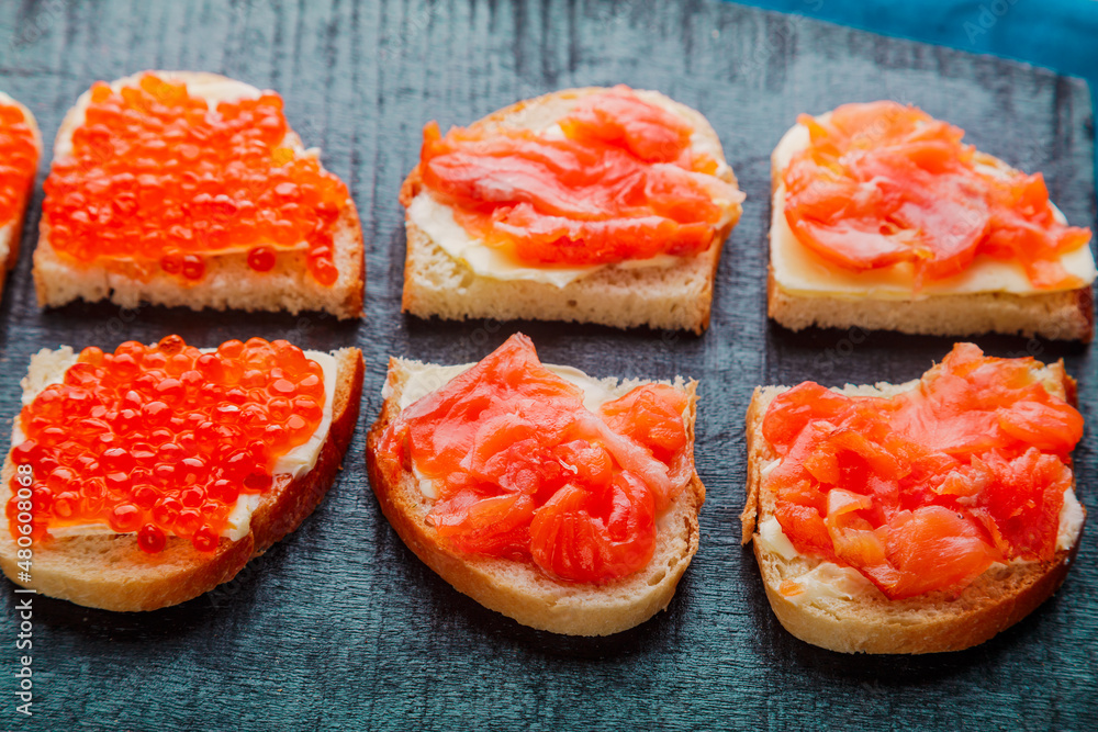 Bruschetta with trout and red caviar on a black board. Bruschetta with trout and red caviar on a black board.