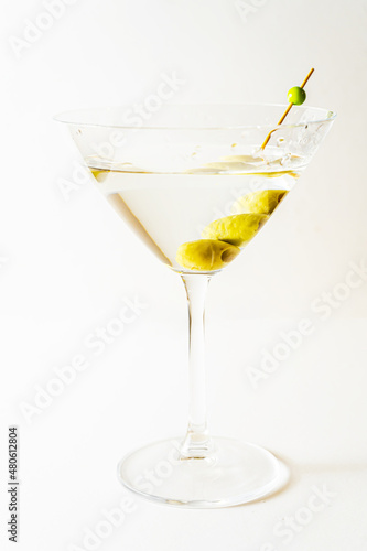 martini glass with olives in vertical orientation with white background.