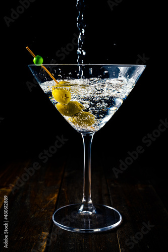 Vertical view of a martini glass with olives being served with the shot from above.
