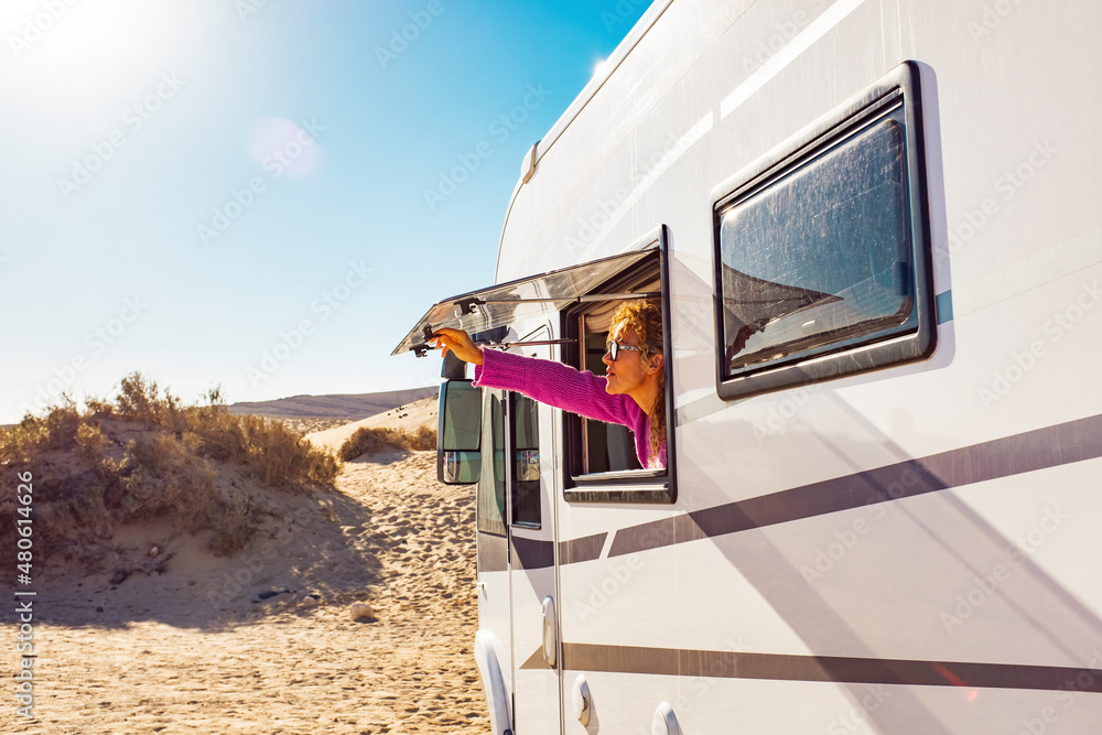 Adult tourist woman opening camper van window to enjoy the sun and freedom. Concept of travel people for summer holiday vacation inside camping car motorhome vehicle. Freedom nomad lifestyle - obrazy, fototapety, plakaty 