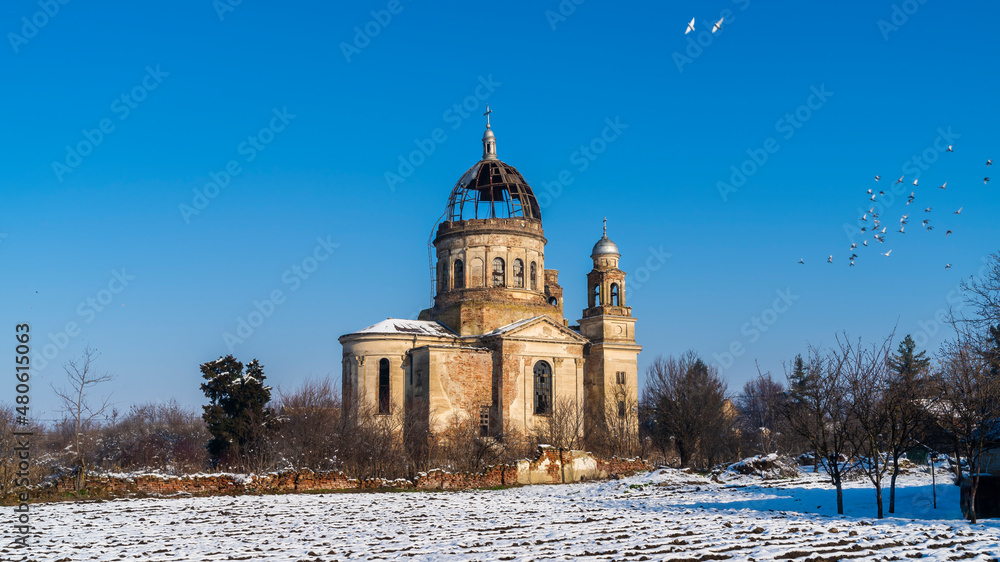 Abandoned mausoleum with ruined dome during winter with birds flying around it