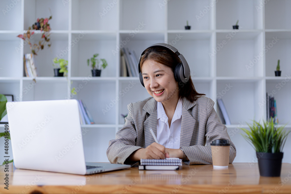 Beautiful Asian woman wearing headphones to study, she is a student, she is going to study online. The concept of online learning due to the COVID-19 outbreak to prevent an outbreak in the classroom. Beautiful Asian woman wearing headphones to study, she is a student, she is going to study online. The concept of online learning due to the COVID-19 outbreak to prevent an outbreak in the classroom.