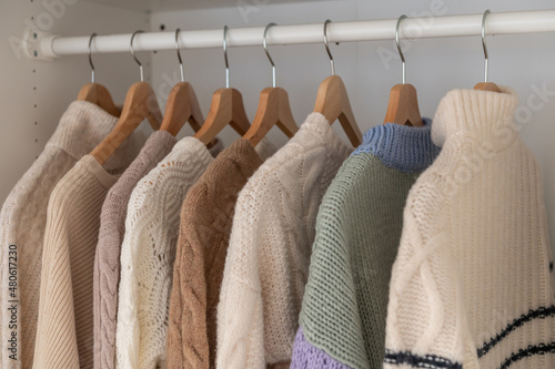 Warm beige wool pullover and knitwear and hanging in wardrobe