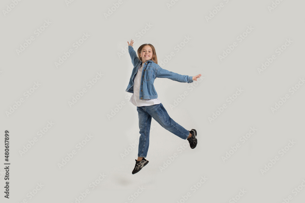 a young girl in jeans jumps with happiness on a white background with a copy of the space