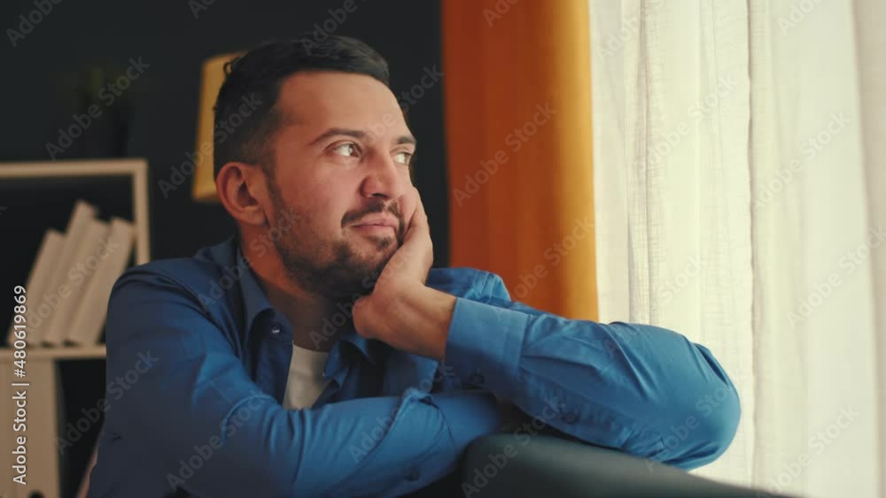 A young man looks out the window of a house. Waiting. A young man looks out the window of a house. Waiting.
