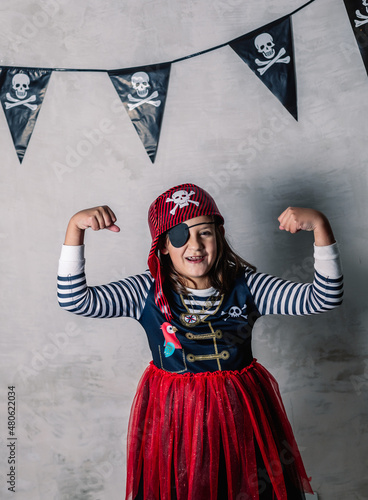 portrait of adorable little girl dressed as a pirate with eye patch and gesturing with strength