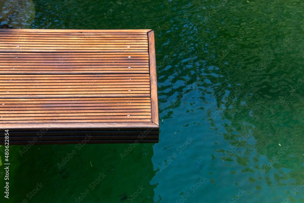 Wooden pier of grooved cumaru hardwood deck on the water close up