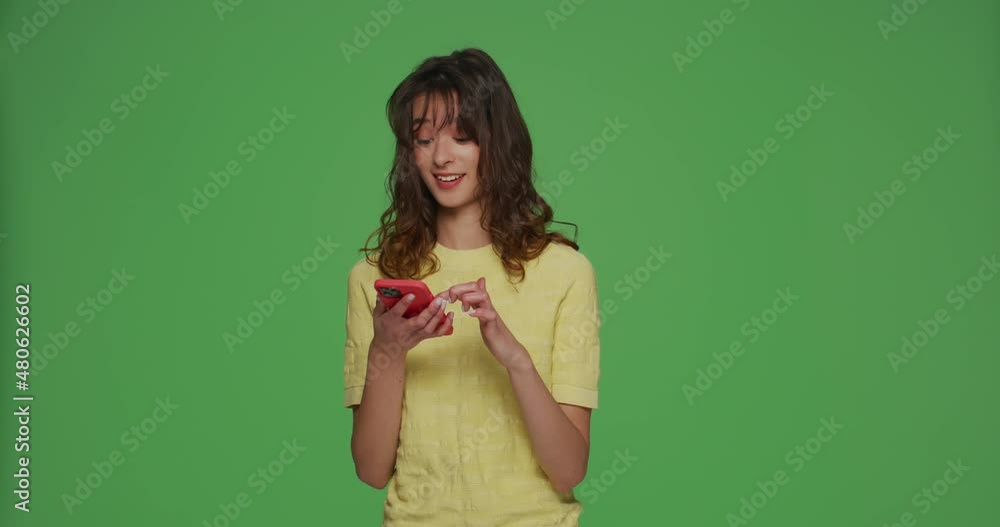 Happy young girl hold phone reading good news in social media watching funny video content on chromakey green background Happy young girl hold phone reading good news in social media watching funny video content on chromakey green background