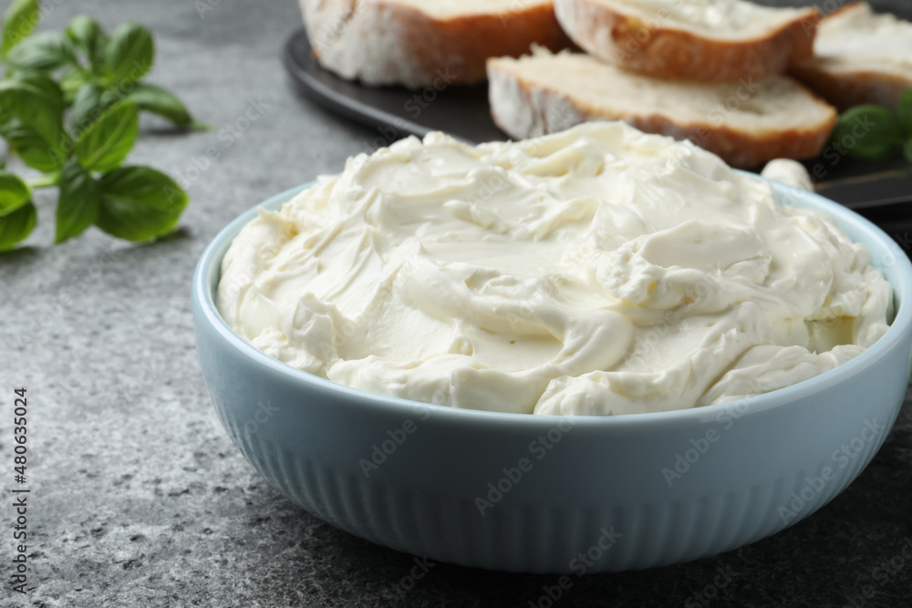 Tasty cream cheese and basil on grey table, closeup Tasty cream cheese and basil on grey table, closeup