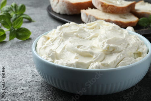 Tasty cream cheese and basil on grey table, closeup