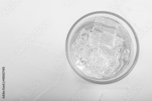 Glass of soda water on white table, top view. Space for text