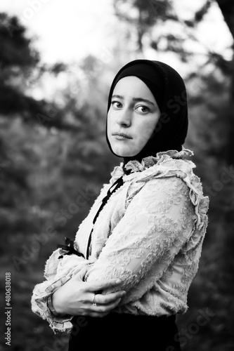 Muslim woman in hijab on the background of trees. Pink blouse and black skirt. Beautiful young woman. Close-up. Black and white photography