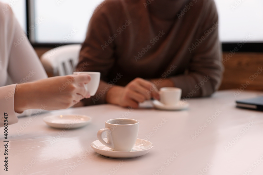 Coworkers enjoying coffee during break in cafe, focus on cup. Space for text Coworkers enjoying coffee during break in cafe, focus on cup. Space for text