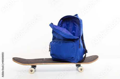 Blue open backpack sitting on skateboard, back to school concept photo