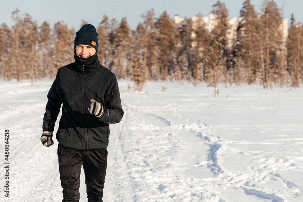 Full length of a happy middle-aged athlete running in nature on a snowy winter day. Outdoor fitness, cardio training, outdoor exercises Full length of a happy middle-aged athlete running in nature on a snowy winter day. Outdoor fitness, cardio training, outdoor exercises