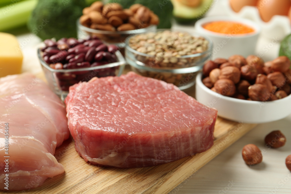 Fresh meat and other products on white wooden table, closeup. Sources of essential amino acids