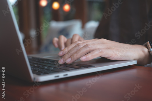 Woman hands typing on laptop computer on wooden table at home or coffee shop, searching information on web, browsing the internet, work from anywhere