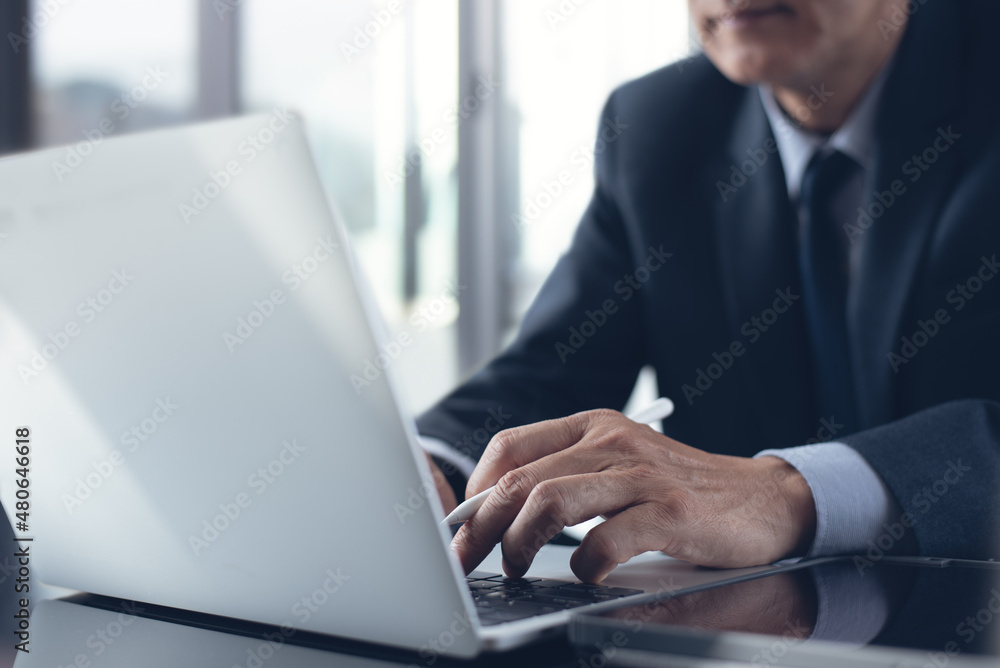 Asian businessman surfing the internet during working on laptop computer at office with digital tablet on table Asian businessman surfing the internet during working on laptop computer at office with digital tablet on table