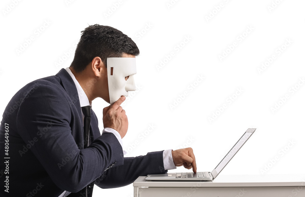 Hacker with laptop and mask at table on white background Hacker with laptop and mask at table on white background