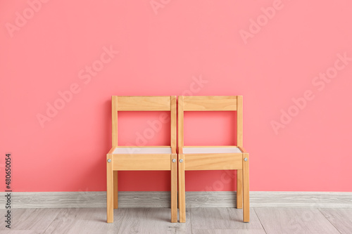 Wooden child chairs near color wall