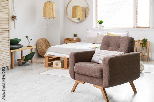 Comfortable armchair with pillow in light bedroom interior