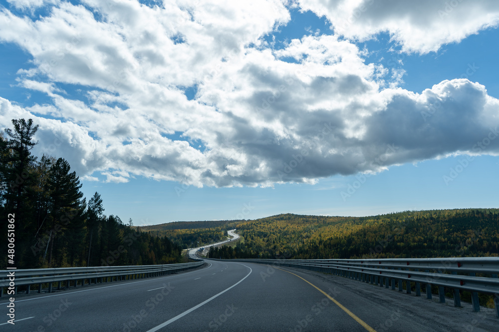 Fototapeta premium A landscape with a winding highway under a cloudy sky.