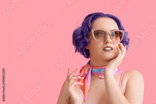 Beautiful young woman with violet hair on pink background. Very Peri - color of year 2022