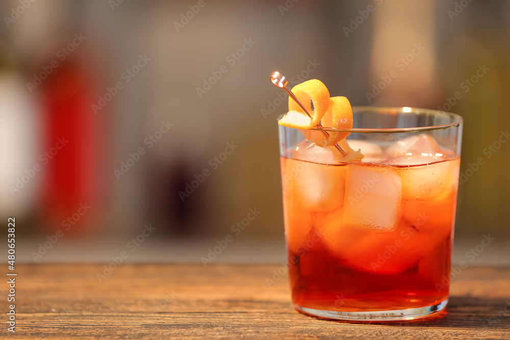 Glass of tasty Negroni cocktail on table against blurred background Glass of tasty Negroni cocktail on table against blurred background