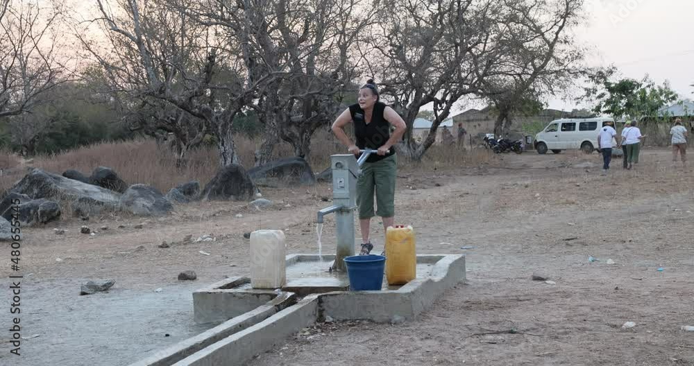 Sherri pumping fresh water borehole well northern Ghana. Remote northern Savannah region. Wells or water pumps placed near village as only source of clean water for drinking, cooking and washing. Sherri pumping fresh water borehole well northern Ghana. Remote northern Savannah region. Wells or water pumps placed near village as only source of clean water for drinking, cooking and washing.