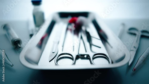 Medical instruments in steel tray on table for surgery. Preparing of surgical tools for a operation. Scalpels and forceps and tweezers. Surgery or emergency case and ambulance or treatment concept.