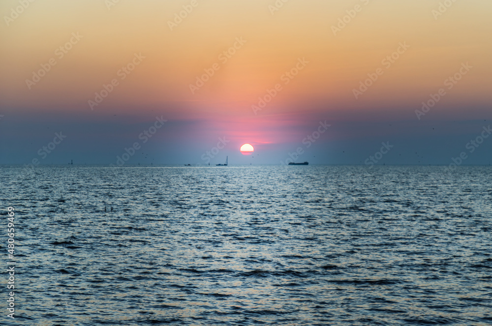 Beautiful sunset over a calm sea with a blue and orange glowing sky. Space for text, Selective focus.